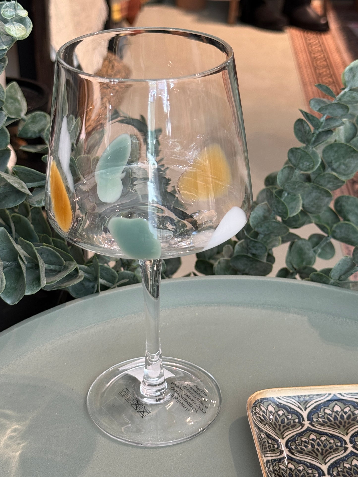 Het wijnglas Gildor van Bloomingville, te koop bij Wanted by DaS in eindhoven, is mondgeblazen en gedecoreerd met gekleurd glas met oranje en groene kleur. Omdat het handwerk is, is elk glas uniek. The Gildor Wine Glass by Bloomingville is mouthblown and decorated with colored glass droplets, in green and orange tones, fused into the clear glass. As placement and shape of the dots vary, each glass has its own character.